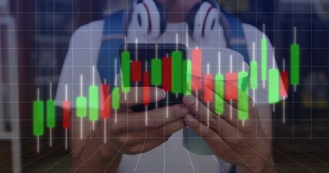 Indian man holding smartphone checking candlestick trading chart in cafe with headphones