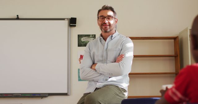 Confident Teacher Sitting on Desk in Classroom - Download Free Stock Images Pikwizard.com