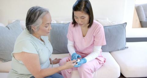 Healthcare worker in pink scrubs assisting senior woman