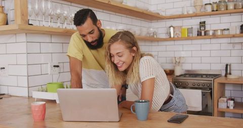 Happy Couple Relaxing in Modern Kitchen Using Laptop