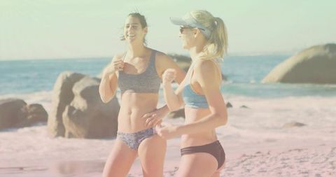 Two Women Chatting Wearing Swimwear on Sunny Beachfront