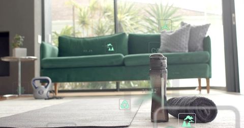 Sunlit home fitness scene featuring water bottle, towel and kettlebell on yoga mat