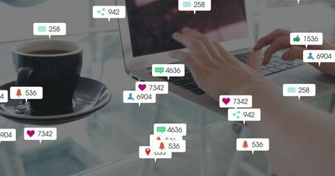 Typing on laptop with floating social media notifications and coffee on glass desk