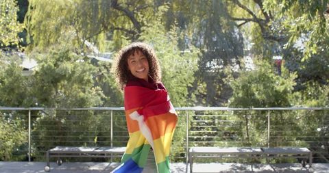 Joyful Young Woman Embracing Pride Flag Outdoors