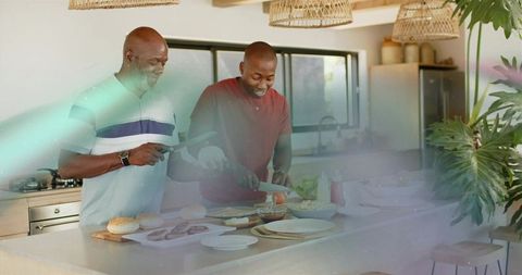 Father and son preparing burgers on sunlit kitchen island, smiling over meal prep