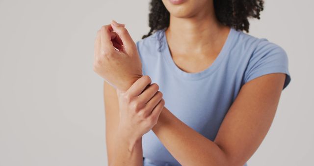 Close-up of a woman massaging her wrist due to pain or discomfort. She is wearing casual clothing, emphasizing a health or rehabilitation concept. Perfect for use in health care articles, physical therapy guides, or home remedy websites.