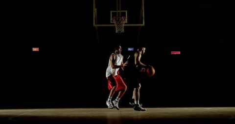 Spotlight basketball showdown dribbling guard evading defender on hardwood court