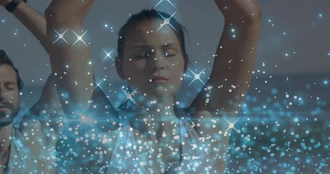 Woman raising arms during yoga with blue bokeh sparkles and wristband, calm mindfulness