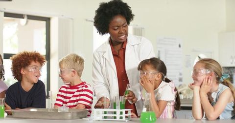 African american teacher guiding elementary students during hands-on chemistry experiment
