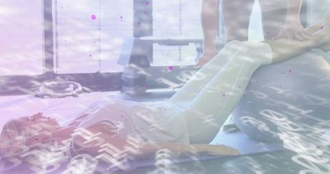 Pilates trainer supporting client performing leg stretch on ball for rehab and strength