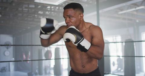 Boxer holding guard training in ring with black and white gloves showing focus and power