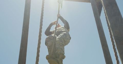 Female soldier climbing rope on obstacle course training