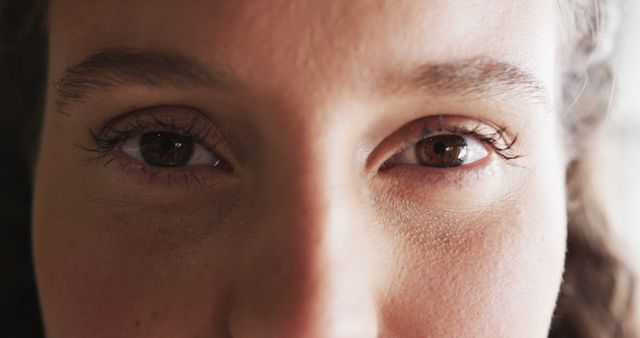 Close-up view of a young woman's eyes in natural light, capturing the details and expression in her gaze. Ideal for use in articles related to human emotions, facial expressions, eye health, beauty, and personal care. Suitable for marketing materials, blogs, and educational content focusing on human interactions and psychology.