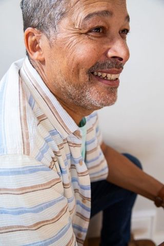 Elderly Man Smiling While Sitting in Stripe Shirt