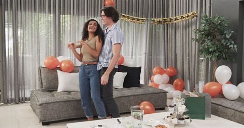 Joyful Couple Dancing at Birthday Celebration in Living Room