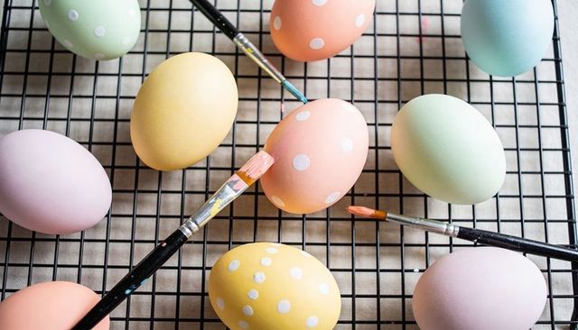 Pastel polka-dot easter eggs drying on cooling rack with paintbrushes