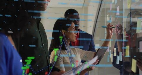 Team collaborating at glass wall mapping strategy with tablet, sticky notes and analytics