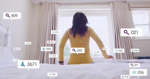 Backlit woman sitting on bed wearing smartwatch with floating social media notifications