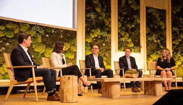 Panelists discussing sustainable business strategies on moss-wall stage at conference
