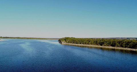 Serene lake and wooded shoreline under clear blue sky