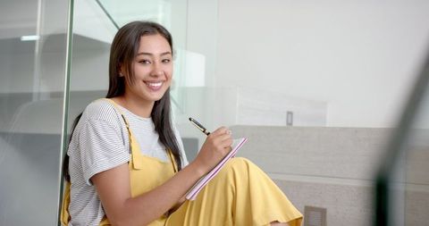 Smiling young woman relishing writing experience