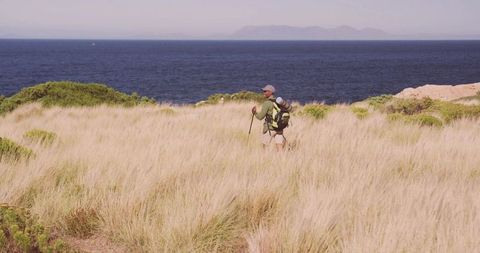 Hiker Trekking on Coastal Dune Near Sea Horizon