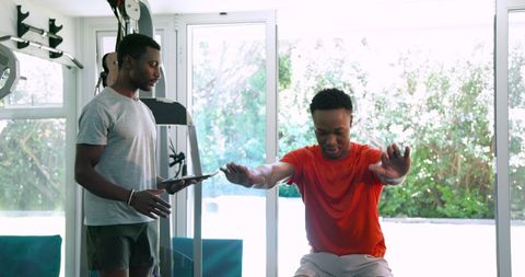 Personal trainer guiding client during squat exercise