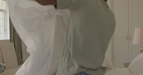 Man Unpacking White Fabric at Home in Bedroom Setting