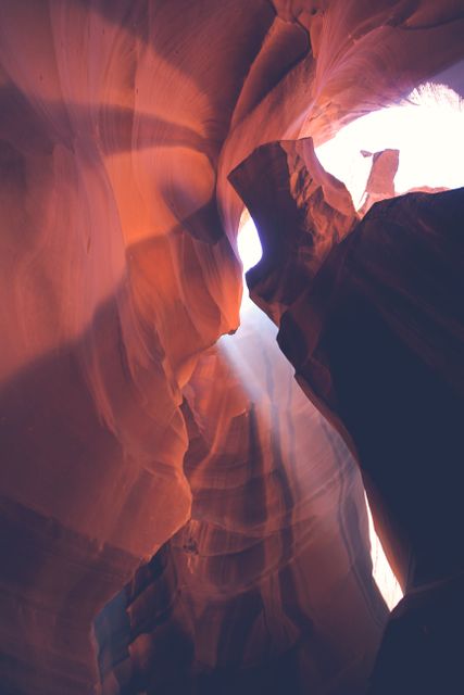 Sunlight gleams through narrow sandstone walls of Antelope Canyon, creating a dramatic play of light and shadows. Perfect for nature and travel themes, or promoting tours to sandstone formations like Antelope Canyon.