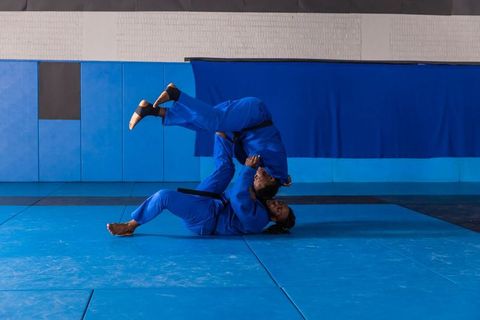 Martial Artists in Blue Gis Practicing Grappling Technique in Dojo