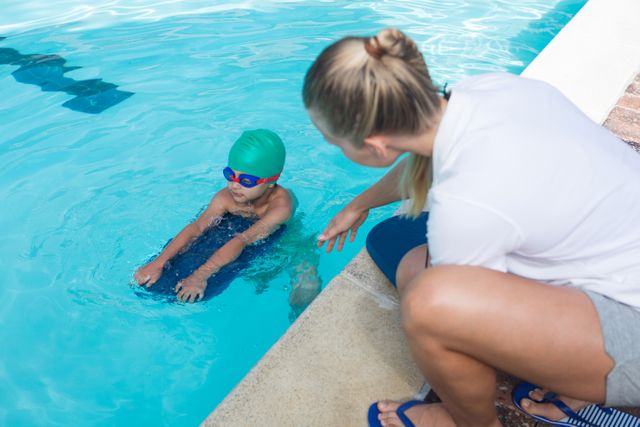 Female trainer training a boy for swimming at the leisure center