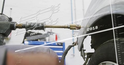 Spot-welding torch aiming at torn car fender with digital overlays, auto body repair concept