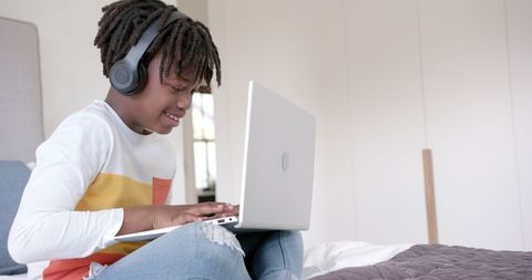 Smiling Boy With Headphones Using Laptop on Bed at Home - Download Free Stock Images Pikwizard.com