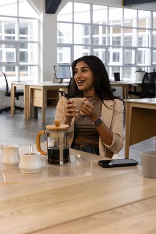 Indian professional enjoying coffee break in modern coworking lounge with french press