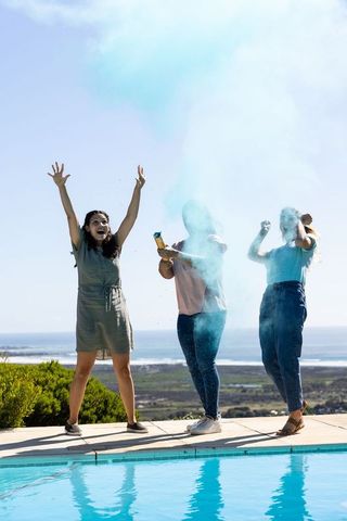 Friends Celebrating with Blue Powder over Poolside View
