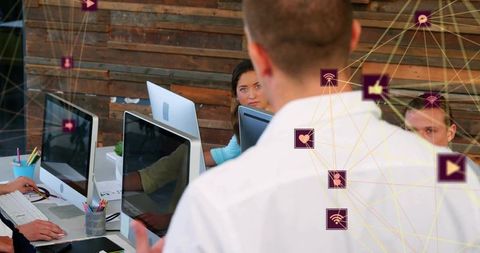 Leader presenting to team in modern office with desktop computers, collaborative teamwork