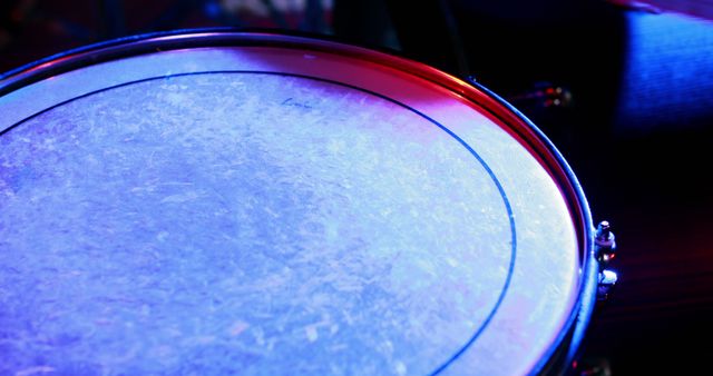 Close-up of a drum head illuminated by red and blue stage lights. Perfect image for use in music-related articles and blogs, concert promotions, musical instrument catalogs, and event advertisements.