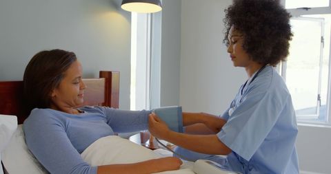 Caring African American Nurse Checking Patient's Blood Pressure