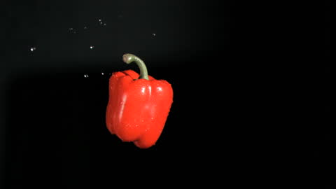 Red Bell Pepper Floating Against Black Background