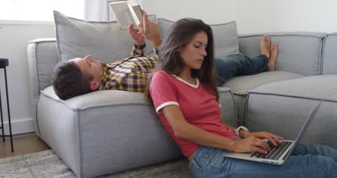 Relaxed Couple Enjoying Leisure at Home with Laptop and Book