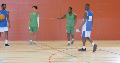 Players dribbling crossover passing laughing indoor basketball team midcourt