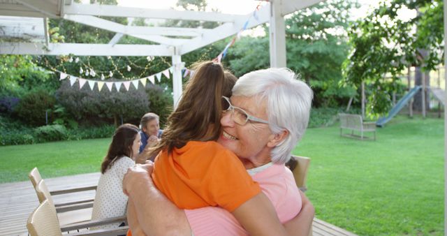 Smiling Grandmother Hugging Granddaughter Outdoors at Family Gathering - Download Free Stock Images Pikwizard.com