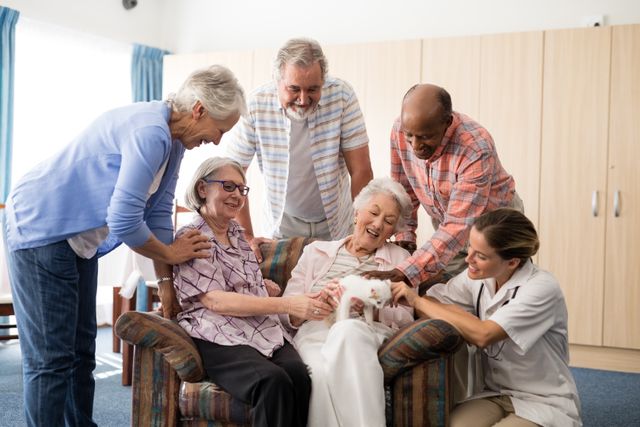 Group of cheerful senior people and a caregiver enjoying time together while playing with a kitten in a nursing home. Ideal for use in healthcare, senior living, pet therapy, and retirement community promotional materials. Highlights the importance of companionship, interaction, and happiness in elderly care settings.