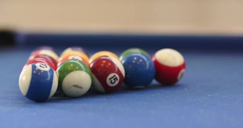 Resting glossy pool balls on blue felt, closeup rack with vibrant stripes and reflections