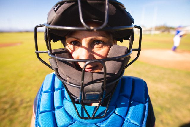 Caucasian female baseball player wearing catcher's gear, looking directly at camera with a focused expression. Ideal for use in sports-related articles, youth sports promotions, team spirit campaigns, and athletic training materials.