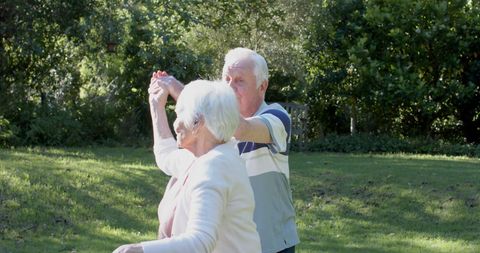 Senior Couple Enjoying Dance Outdoors in Sunlit Garden