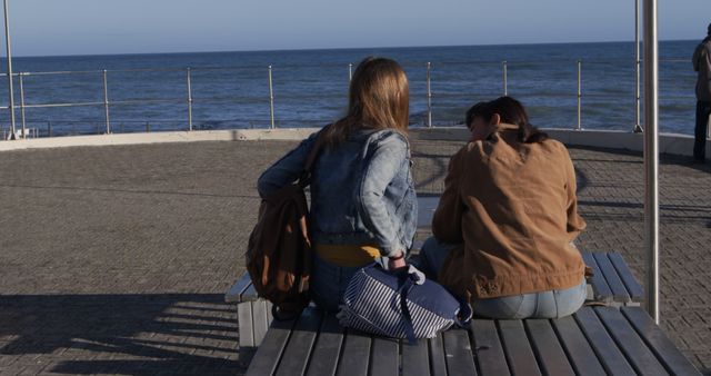 Two Women Sitting on Bench by Ocean Discussing - Download Free Stock Images Pikwizard.com