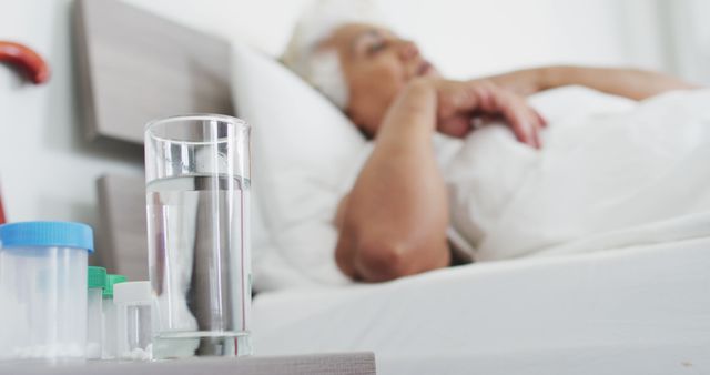 Sick african american senior woman drinking water while lying on the bed at home - Download Free Stock Photos Pikwizard.com