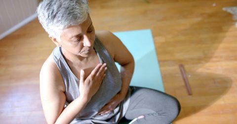 Senior Woman Meditating on Yoga Mat at Home