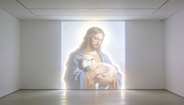 Illuminated devotional projection of jesus holding lamb on minimalist gallery wall